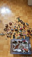 Full view of assortment of fishing and Christmas ornaments spread on floor with plastic container holding more ornaments