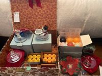 Wide view of all items including aroma melts, ceramic snowman holder, crystal candle holders, and poinsettia holder displayed on table.