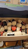 Plastic storage bin filled with multiple skeins of natural colored Red Heart yarn.