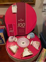 Round anniversary box opened showing five teacups and saucers with booklet