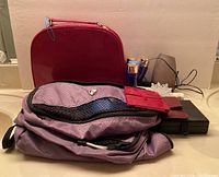Overview photo of makeup case, purple storage bag, hand mirror, plug-in scent diffuser, nail care box, and miscellaneous items arranged on tabletop.