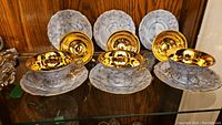 Front view of 3 sets of teacups with saucers showing gold interior of cups and marbled blue-white exterior.