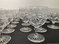 Close-up of several crystal glasses showing detailed cut patterns and the stems. Two large glasses with chips on their rims visible.