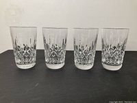 Four clear Waterford crystal tumblers in a row showing side view and size consistency