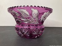 Side view showing the bowl shape, scalloped rim, and leaf and flower cut details on amethyst crystal.