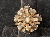 Close-up top view of ring cluster showing central and surrounding oval cabochon stones in gold setting