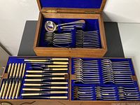 Canteen opened showing top serving tray with ladle and sugar tongs, plus two lower trays with knives, forks and spoons