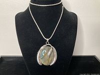 Full view of the pendant hanging on the chain displayed on a black mannequin bust showing the Art Nouveau style design and labradorite stone.