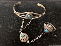 Full view of the Navajo sterling silver bracelet connected by chain to the ring, both featuring turquoise stones.