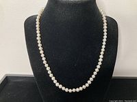 Necklace displayed on a black bust showing full strand of pearls