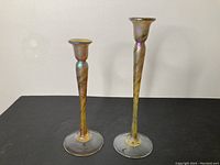 Pair of Robert Held glass candle holders side by side on black surface.