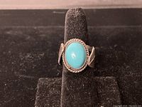 Front view of sterling silver ring with oval turquoise cabochon and twisted rope bezel.