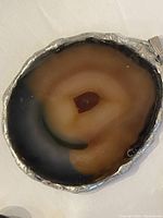 Close-up of large round agate stone pendant with concentric color bands in silver-tone bezel