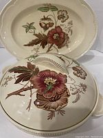 Oval platter and covered serving dish showing floral design and textured rims