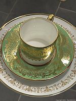 Photo showing close-up of a Coalport demi cup and matching saucer with apple green and gold detailing