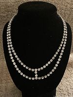 Full front view of the double-row necklace featuring clear stones in claw settings on a black background.