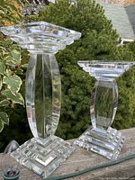 Photo of both crystal candle holders side by side outdoors with greenery background showing heights and design