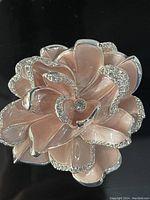 Front view of pale pink enamel and rhinestone flower brooch pin on black background