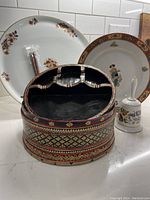 Group photo showing the Limoges charger plate, the hand-painted oriental box, the Fitz and Floyd dinner bell, and the chopsticks alongside the plate.