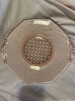 Top view of the pink depression glass cake plate showing etched center design and octagonal shape with handles.