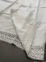 Close-up showing detailed lace work around edge of the linen tablecloth, highlighting fabric texture and stitching.