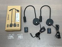 Two black wall-mounted LED reading lights with flexible arms, USB cords, power adapters and original box on a grey surface.