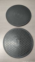 Two round black swivel rotating bases with textured top surfaces shown from above