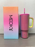 Image showing tumbler next to its colorful pink to blue gradient box with 'Meokoe' branding.