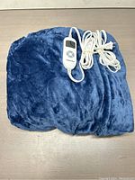 Blue soft plush flannel heated throw blanket folded with controller cable coiled on top.