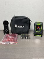 Overall lot view showing Huepar laser level, carrying case, tripod adapter, target plate, and batteries.