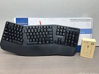Ergonomic wireless keyboard with cushioned palm rest in front of its original box, next to a boxed wireless mouse