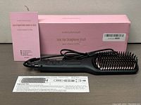 Megawise Ionic Hair Straightener Brush with pink box, user manual, and instructional paper insert laid out on surface