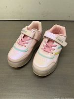Top view of pink kids roller shoes showing laces, velcro strap, and rainbow detail.