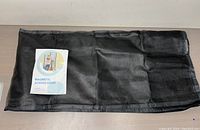 Folded black mesh magnetic screen door with instruction manual placed on top, laid out on a surface.