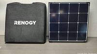Folded solar panel assembly next to Renogy-branded storage case