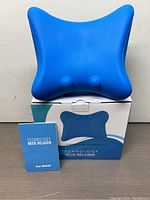 Technology Neck Relaxer device shown with user manual and original box, photo taken to display the complete lot.