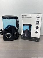 Front view of Turewell water flosser next to original product box showing features and branding.