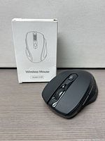 Black ergonomic wireless mouse placed beside its white retail box showing line drawing and model number D-09.
