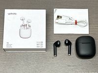 Yobola T9 Bluetooth earbuds with original white retail box, black earbuds and charging case, white USB charging cable wrapped with red twist tie, laid out on a white surface.