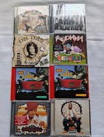 Photo of 8 hip hop CD albums arranged in two columns of four. Visible titles include Naughty by Nature, Bone Thugs-N-Harmony, Dr. Dre The Chronic Re-Lit, Redman Malpractice, Salsa volumes 1 and 2, The Roots The Tipping Point, and Notorious B.I.G. Life After Death.