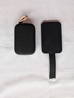 Photo of the Sapporo mini speaker in its black mesh fabric case with beige carrying loop and the RAVPower portable charger with built-in USB cable and plus/minus markings on cable