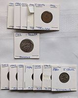 Image showing 13 coins from Australia, Trinidad, and Barbados in protective sleeves with handwritten year and country labels