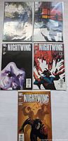 Photo of 5 Nightwing comic books laid flat, each with distinct cover artwork, all from DC Comics, in protective sleeves.