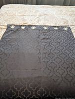 Single curtain panel laid flat showing the overall geometric pattern and metal grommets at the top.