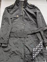 Full view of the Ivanka Trump black coat showing front button details and shoulder epaulets with metal buttons.