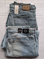 Two folded pairs of denim bottoms; jeans on top with Signature Label Urban leather patch and shorts underneath with Airwalk label
