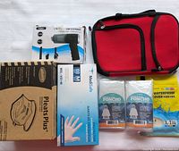 Mini red pouch, USB vacuum cleaner box, face masks box, glove box, two packs of ponchos, yellow shoe cover package laid out on a white surface.