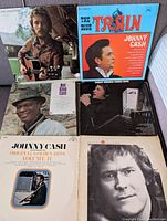 Five vinyl record albums featuring Nat King Cole, Johnny Cash, and Gordon Lightfoot on a fabric surface.
