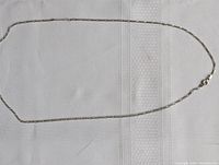 Full view of the silver chain laid flat showing the entire length and clasp.