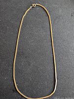 Full length of gold tone bicycle link style chain necklace on black background.